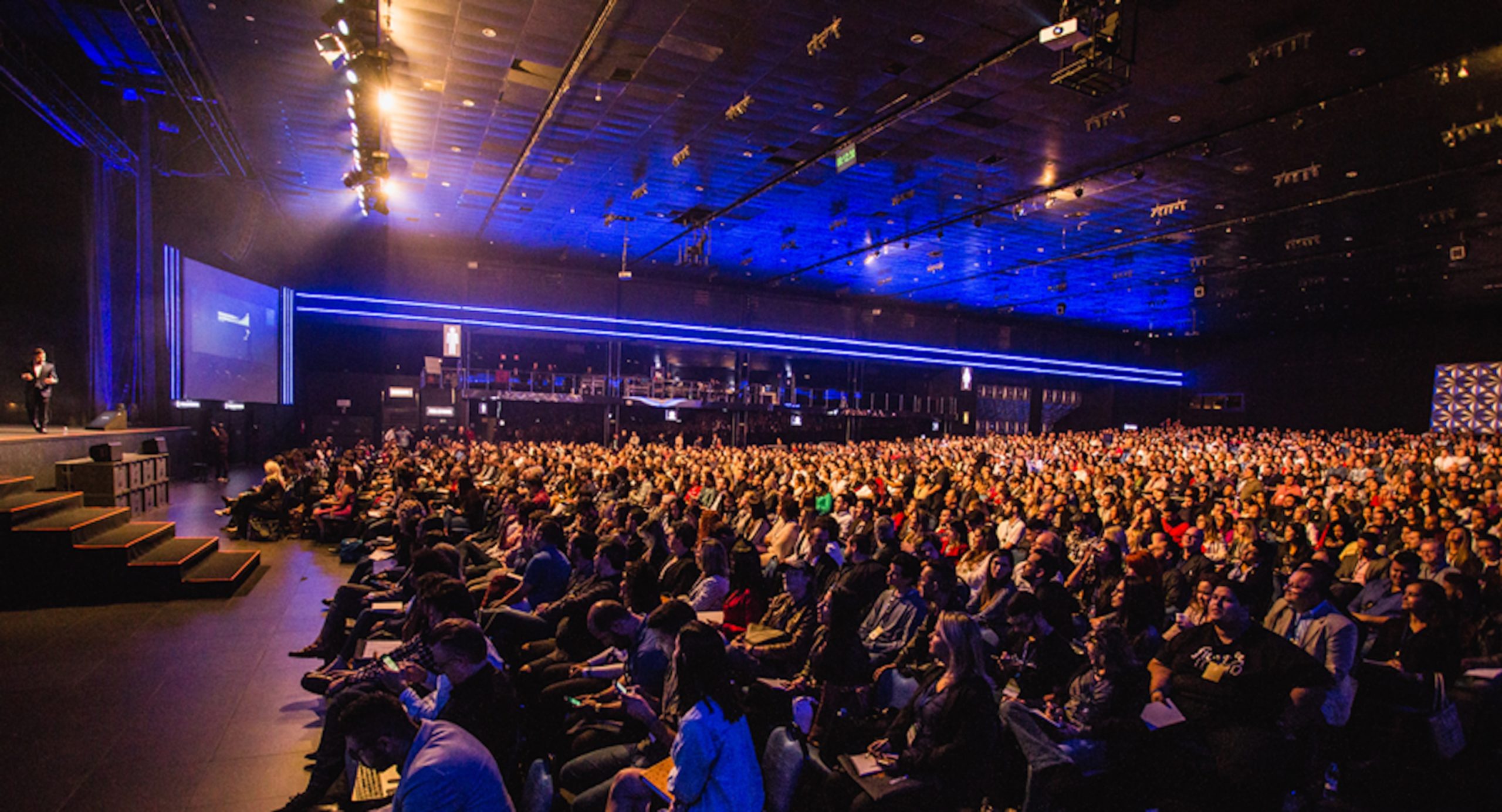 A speaker on stage in front of a large audience